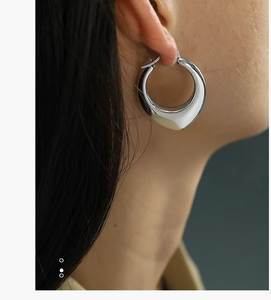 Macro view of chunky silver U-shape hoop earrings in polished stainless steel