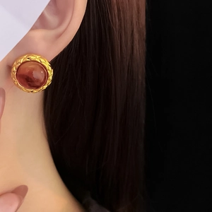 Close-up of vintage geometric gold earring with brown resin stone on model ear
