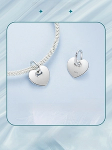 Macro view of a polished heart-shaped S925 sterling silver pendant on a woven chain