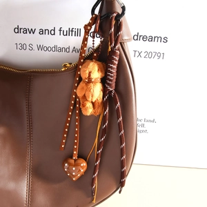 Handmade brown plush bear bag charm with heart pendant on leather bag