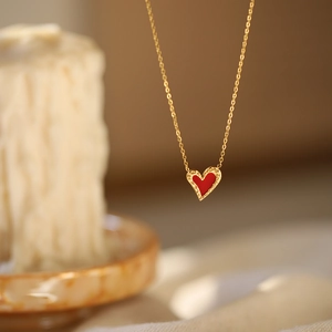 Macro shot of gold heart necklace with red enamel and textured metal edge finish