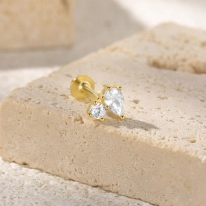Detail of a gold-plated ear piercing with round and teardrop-shaped clear zircons