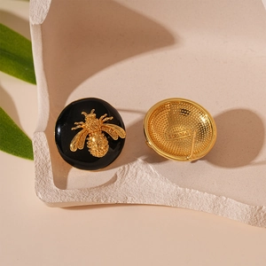 Macro shot of vintage round bee earrings showing detailed enamel and engraved back
