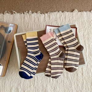 Detailed view of three pairs of vintage striped cotton socks on a wooden tray with a retro vibe