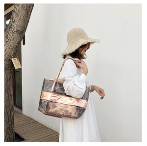 Outdoor shot of a transparent PVC beach bag with rose gold trim and matching inner pouch
