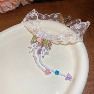 Detail of lace choker with floral charms and a letter pendant in a ceramic dish