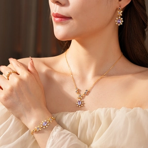 Detailed view of vintage gold flower jewelry set with purple zircon and crystals on a model