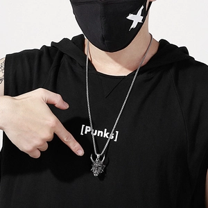 Detail of silver ghost face pendant with box chain worn by male model in dark style