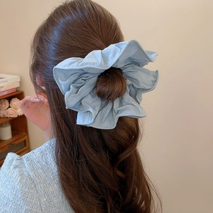 Gros plan d'un chouchou bleu clair à volants sur un chignon dans un intérieur chaleureux