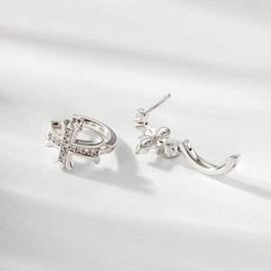 Eleganti orecchini a cerchio in argento con croce e zirconi su superficie bianca