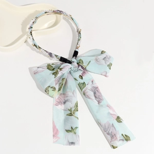 Detail of blue floral headband with elegant pearls and elastic band on a beige tray