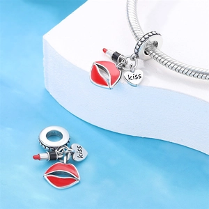 Detail of 925 silver lipstick and heart charm with kiss engraving on a charm bracelet