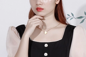 Detailed close-up of a minimalist gold letter L pendant necklace worn on a woman collarbone