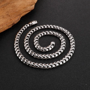 Minimalist silver chain necklace with unique link weave design on a black textured surface