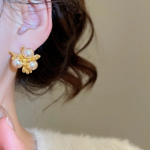 Close-up of vintage gold fireworks earrings with three white pearls on a model