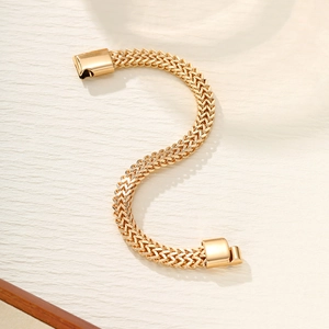 Detailed top view of gold punk bracelet with woven pattern links on beige background