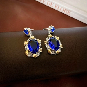Vue détaillée des boucles d'oreilles vintage avec grand zircon bleu sur texture cuir
