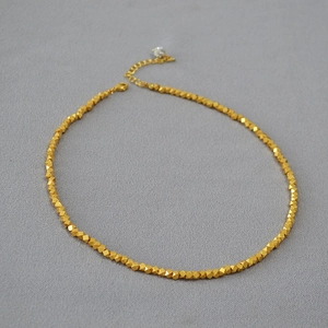 Detailed macro view of a gold-plated irregular bead necklace with a lobster clasp