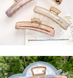Detailed close-up of large acetate shark hair clip with elegant golden metal edging detail
