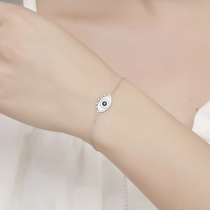 Detailaufnahme eines Silberarmbands mit bösem Blick, Muscheleinlage und Kristallen