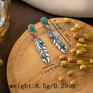 Detailed view of silver bohemian feather earrings with turquoise stone and dimensions