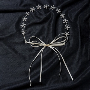 Close-up of golden starfish headpiece with sparkling rhinestones and white ribbon tie
