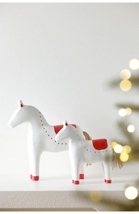 Close-up of white and red Dala horse figurines set with hemp rope tails and festive lighting