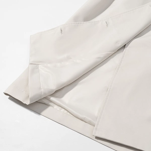 Detailed close-up of premium beige trench coat hem with high-quality lining and fine stitching