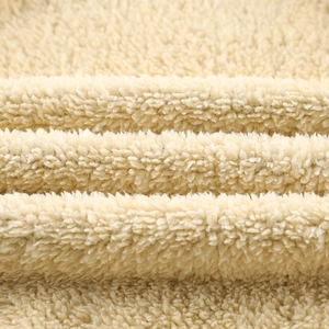Macro view of thick cream fleece fabric texture with soft curly plush fibers