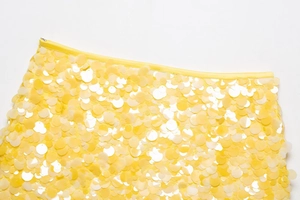 Détail d'une mini-jupe jaune à paillettes avec de grandes paillettes rondes et zip latéral