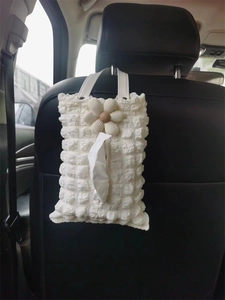 Detail of white bubble texture car tissue holder with daisy on seat backrest