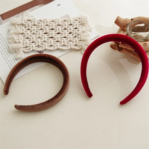 Detail of red and brown velvet padded headbands displayed on a warm decorative setting