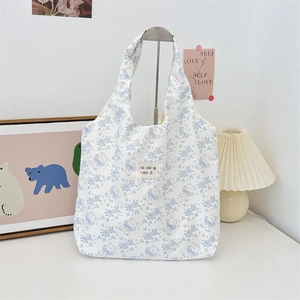 Vue détaillée d'un sac cabas blanc avec motifs de fleurs et ours bleus embossés
