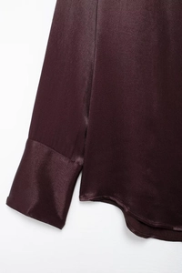 Macro detail of dark burgundy satin shirt showing glossy fabric texture and sleeve cuff