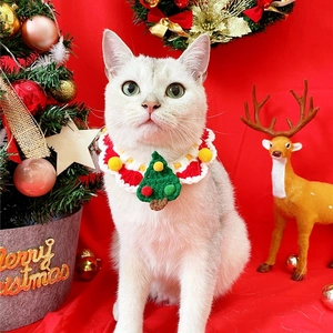 Detail of red and green knitted Christmas cat collar with festive tree and pompom decor