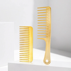 Macro shot of two golden wide-tooth detangling combs on white geometric pedestals