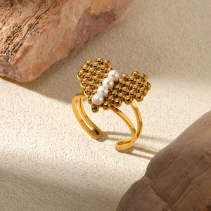 Detail of a golden heart ring with four white pearls on a natural stone background