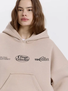 Detail of apricot oversized hoodie with black letter print and warm cotton texture