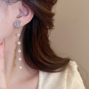 Close-up of model wearing silver tassel earrings with white pearls and sparkling crystals