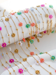 Detail of colorful beaded flower bracelets and anklets with golden stainless steel chain