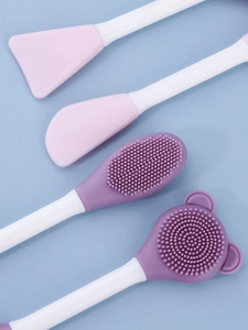 Close-up of pink silicone face mask spatula and purple exfoliating cleansing brush heads