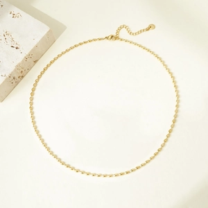 Detailed close-up of golden oval bead necklace with adjustable chain and brand tag