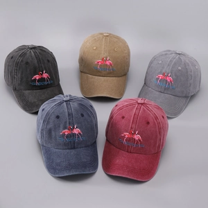 Flat lay of multiple washed cotton baseball caps with flamingo embroidery in five colors