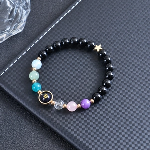 Macro view of beaded bracelet with black obsidian stones and Virgo zodiac charm
