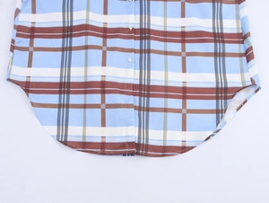 Detailed view of the curved hem and plaid pattern on a blue and brown buttoned shirt dress
