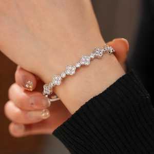 Close-up of a silver clover bracelet with sparkling zircons on a model's wrist