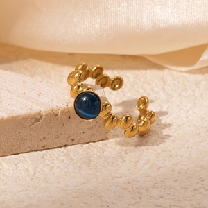 Detailed view of 18K gold plated ring with blue cat-eye stone on beige stone