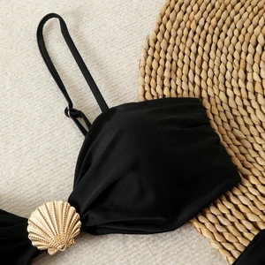 Detail of black bikini top featuring a golden shell buckle and adjustable straps