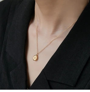 Close-up of a gold teardrop pendant with star engraving on a black blazer background