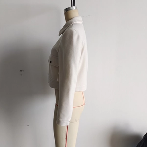 Détail d'une veste en tweed blanc montrant le col, la manche et le rabat de poche